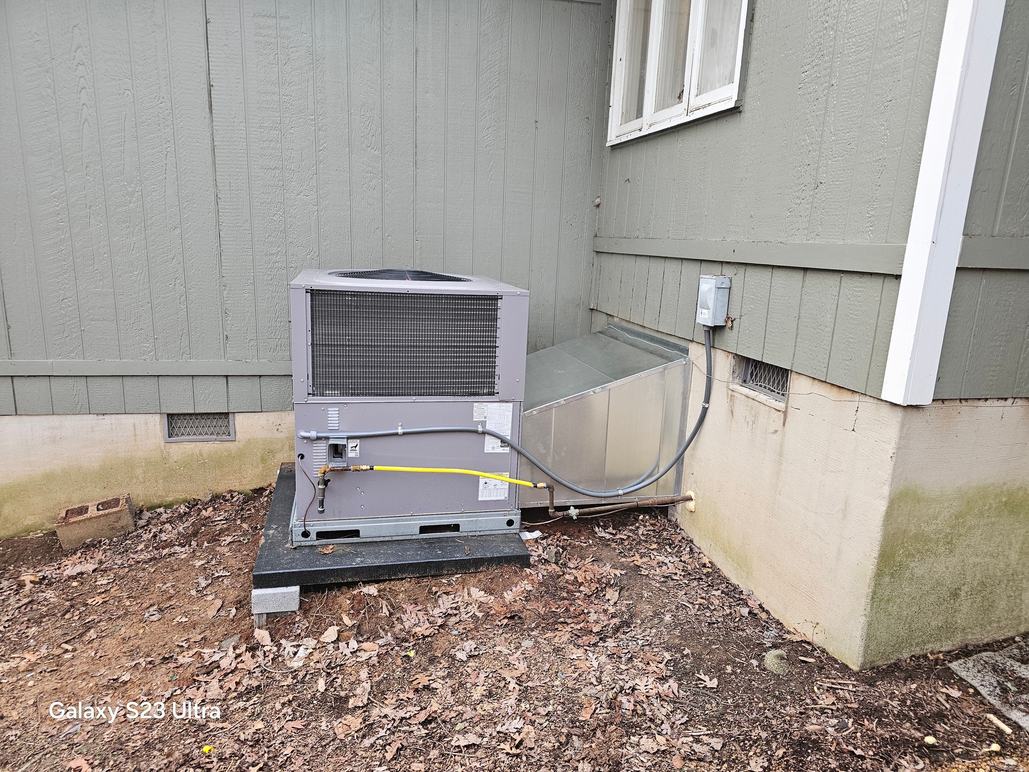 A residential outdoor heat pump condenser sits beside siding on a raised pad in Dunlap, TN — Kilgore Heating and Air