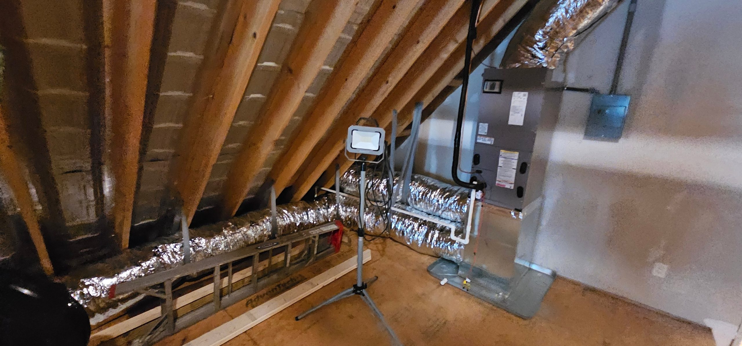 An indoor air handler connects to reflective-insulated flex ducts in a basement — diagnosing water pooling near a furnace