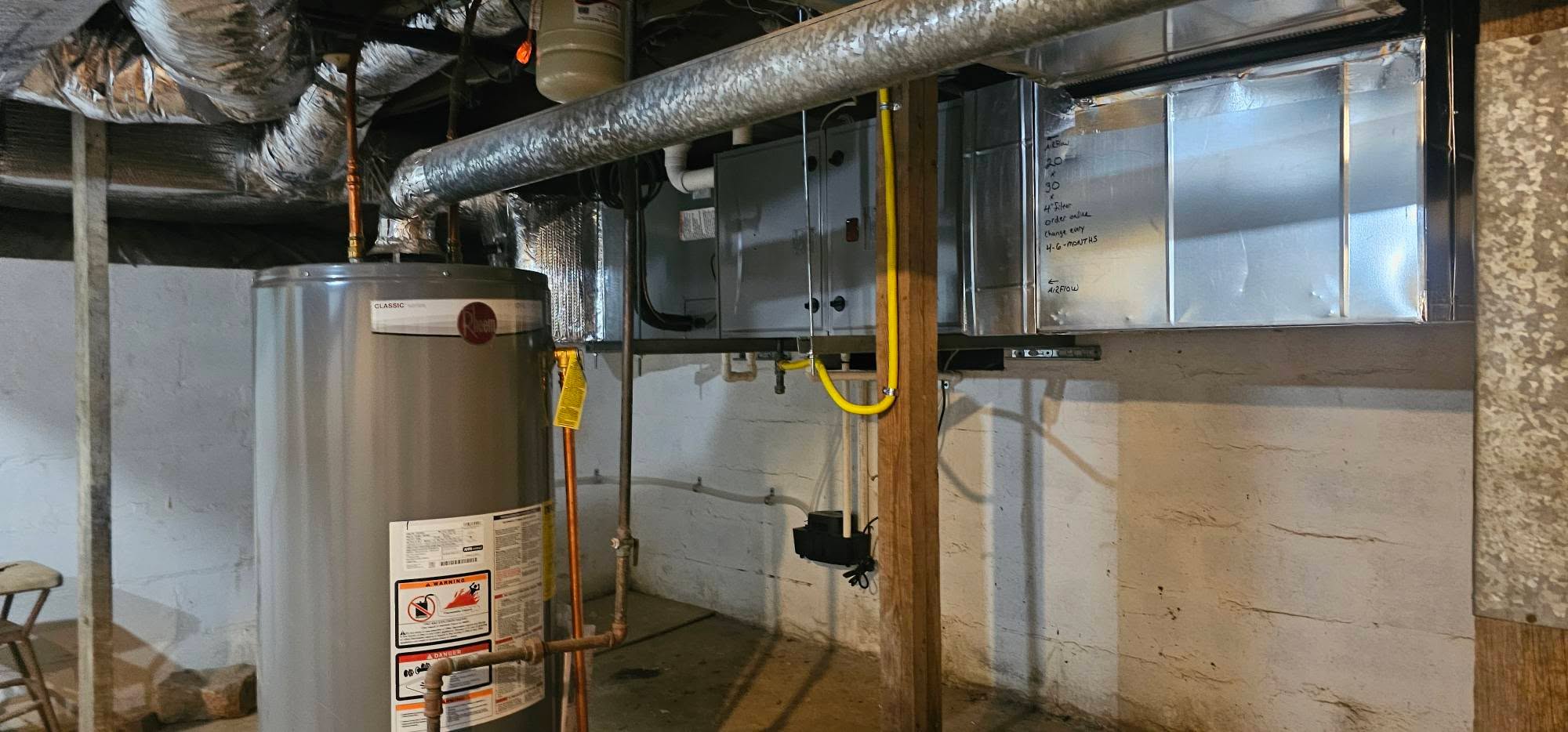 A furnace and rectangular ductwork are installed beside a basement water heater — diagnosing high humidity when the AC runs