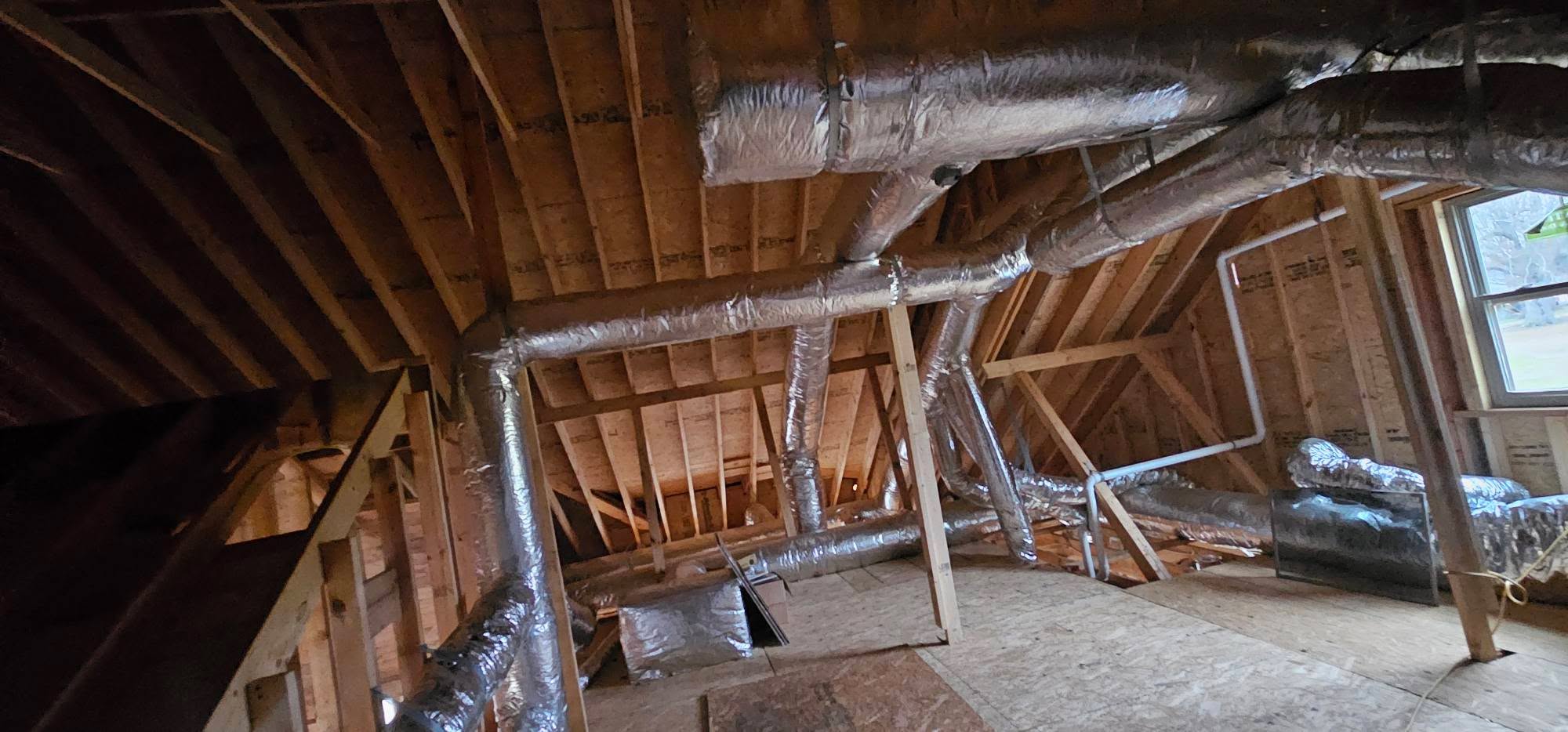 Reflective insulated ducts branch through a framed attic around an indoor unit — diagnosing an AC freezing up