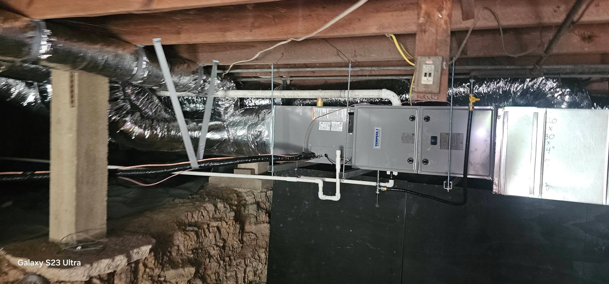 An air handler and connected ductwork are installed beneath a building — diagnosing an AC leaking water