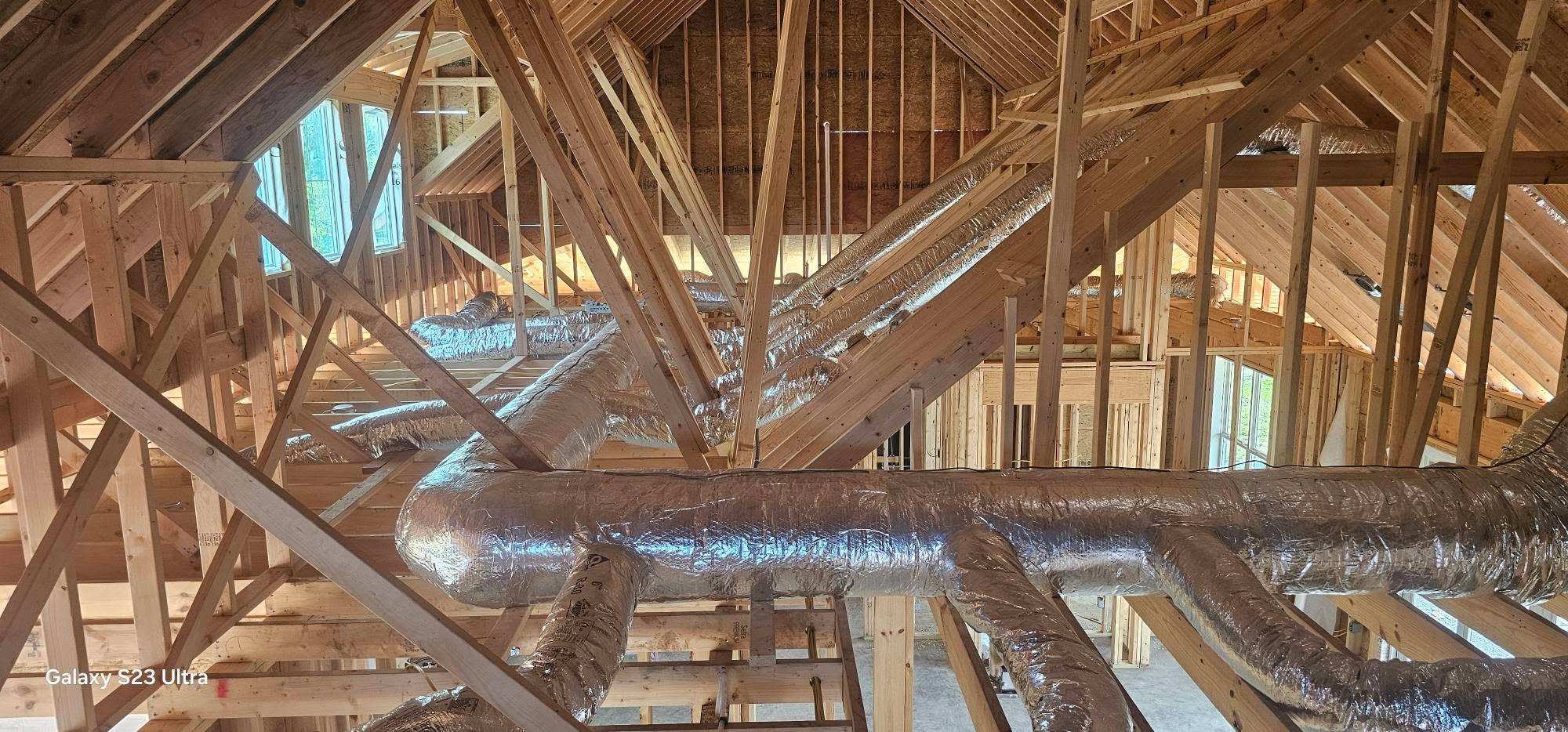 Reflective flex ducts branch across open roof trusses construction — diagnosing whistling ductwork
