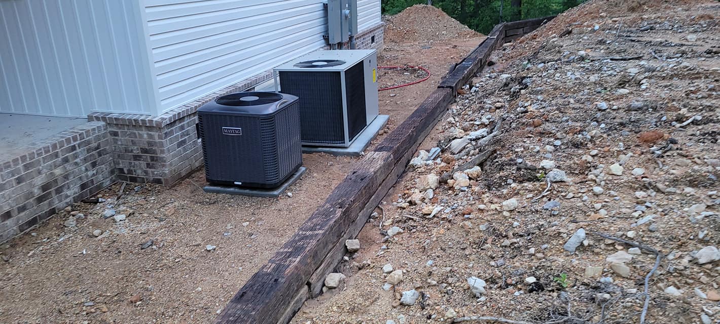 Two outdoor condensers sit beside a new home above a freshly graded exterior strip in Stevenson, AL — Kilgore Heating and Air