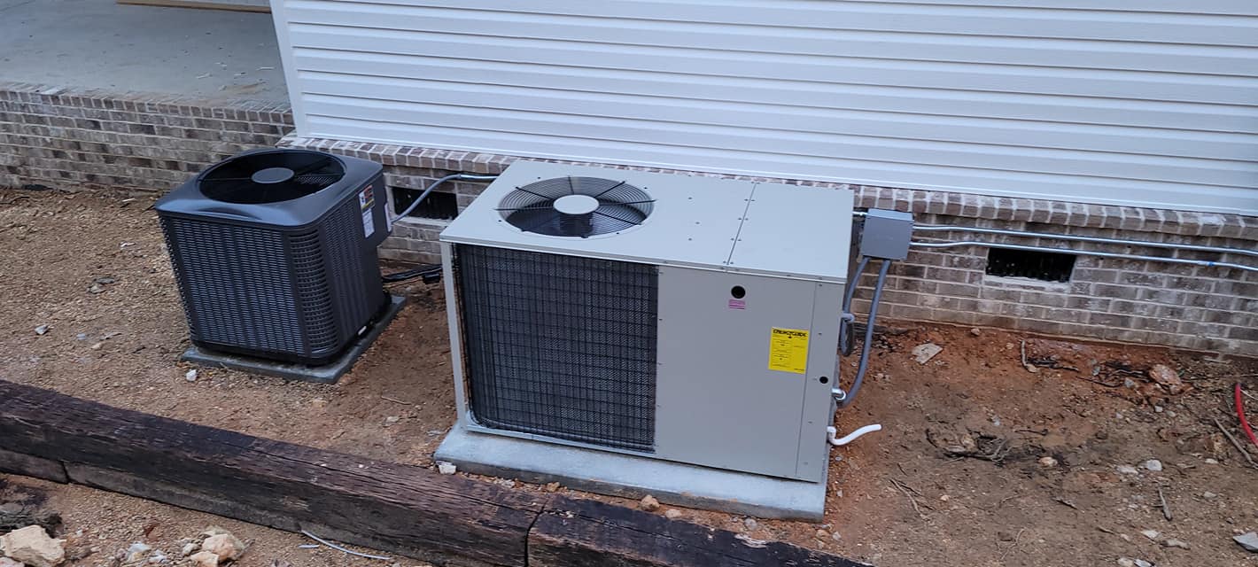 Two central condensers and a larger outdoor unit are installed beside a new home — HVAC troubleshooting