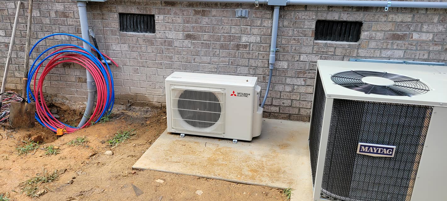A central condenser and a Mitsubishi ductless unit are installed beside a brick home — diagnosing a heat pump running constantly