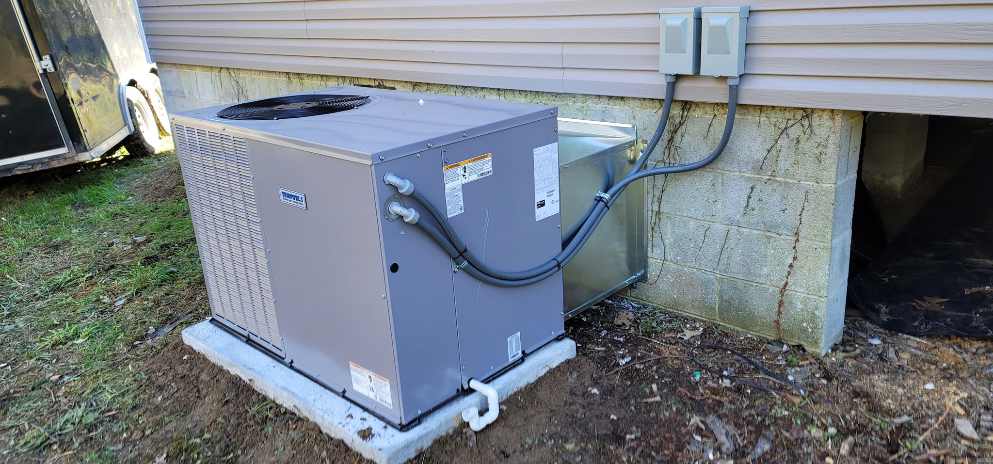 A gray outdoor condenser sits on a concrete pad beside a home's foundation in Trenton, GA — Kilgore Heating and Air
