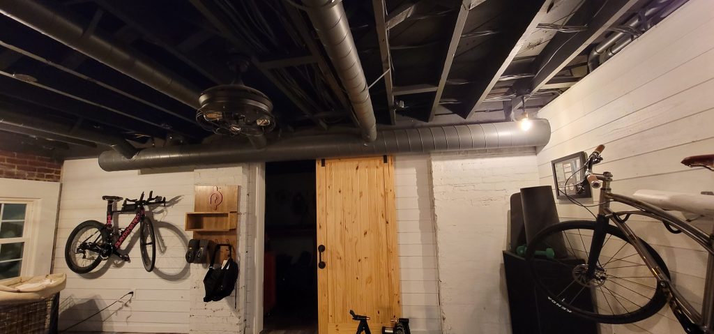 Exposed metal ductwork across a finished basement ceiling
