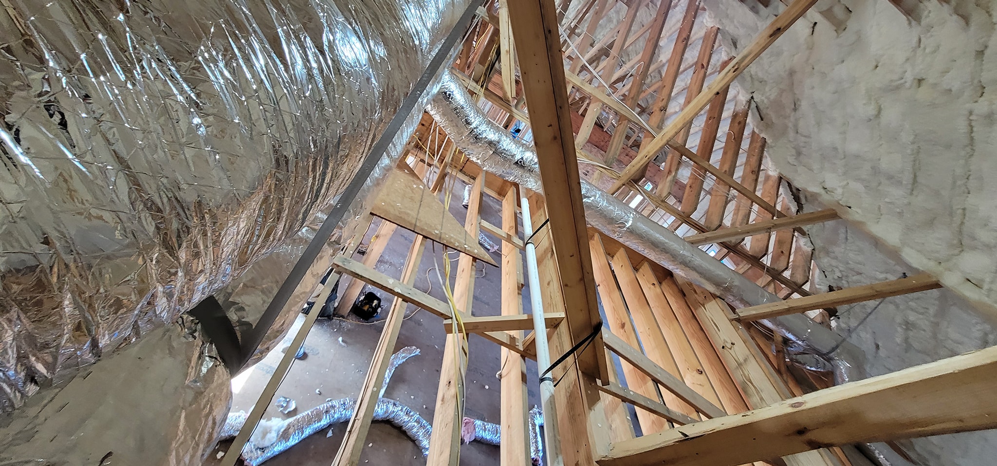 Reflective insulated ductwork runs through a spray-foamed attic space — diagnosing hot and cold rooms in a foam-insulated house