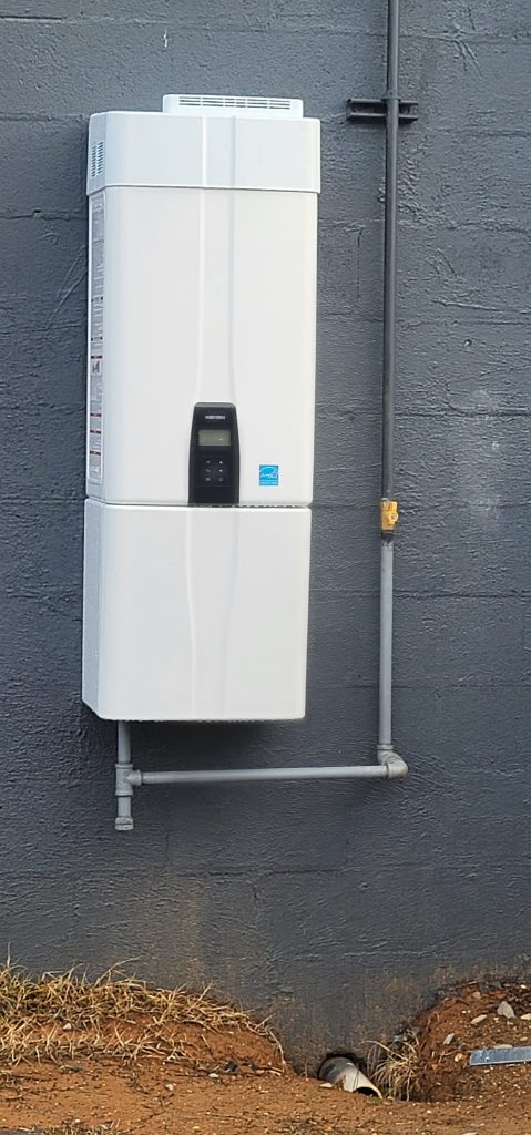 Navien tankless water heater mounted on a masonry exterior wall