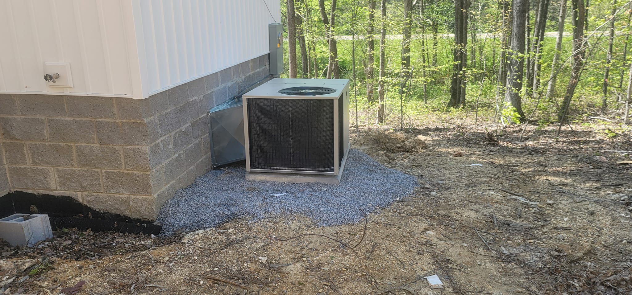 A small outdoor condenser is installed on gravel beside a new home in Tracy City, TN — Kilgore Heating and Air