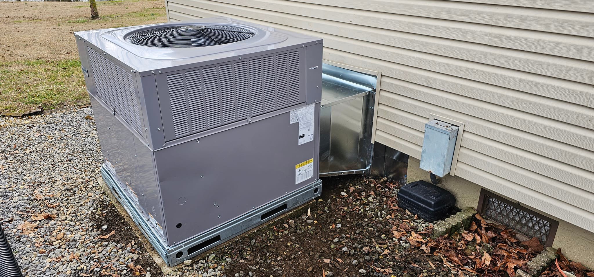 A gray outdoor condenser sits on a pad beside a home’s exterior wall in Whitwell, TN — Kilgore Heating and Air