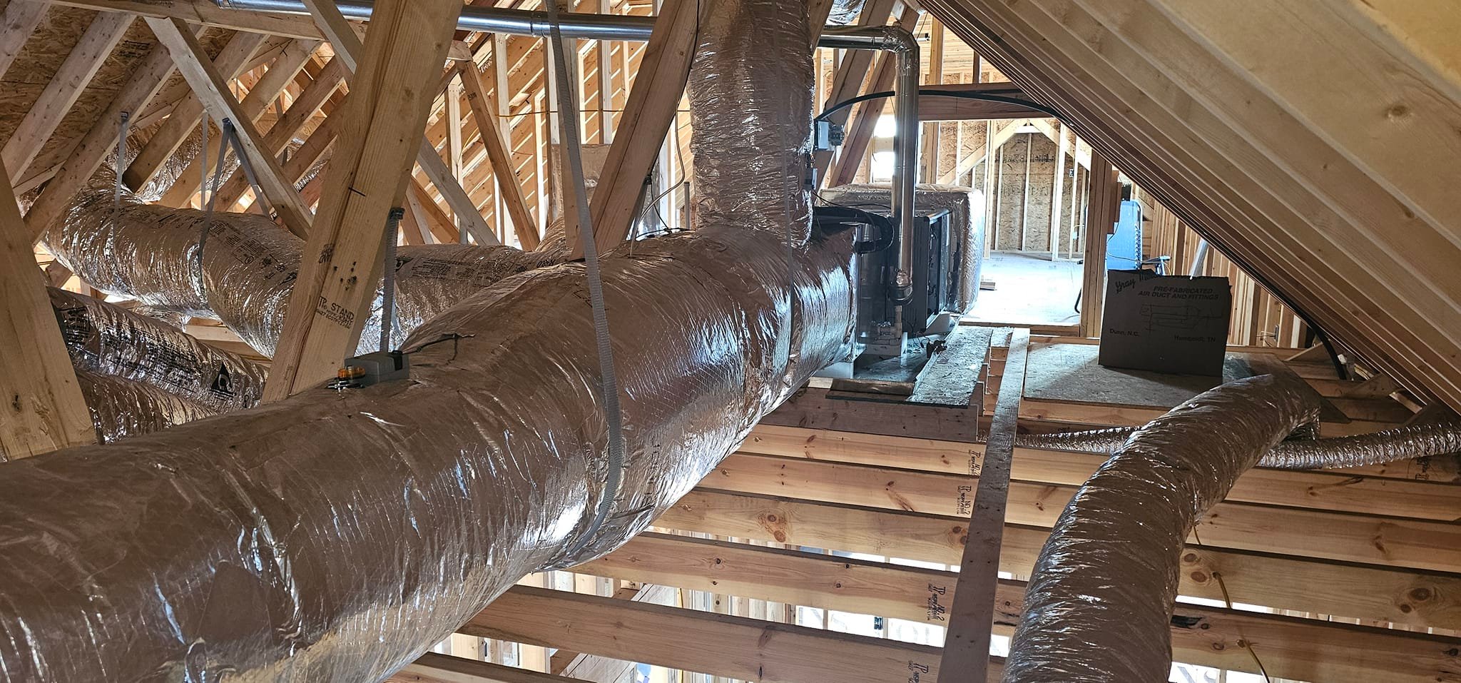 Large reflective flex ducts run across open roof framing in a new house — diagnosing weak return-grille airflow